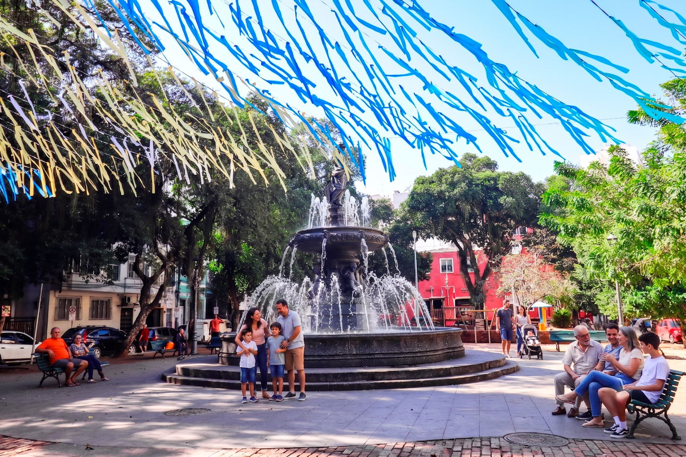 A Praça São Salvador em um domingo, com o chafariz e famílias em volta